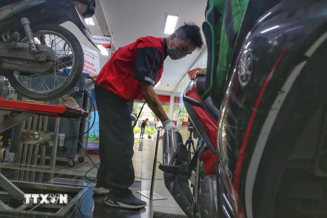 Các nhân viên kiểm tra khí thải xe máy. (Ảnh: Tuấn Đức/TTXVN).